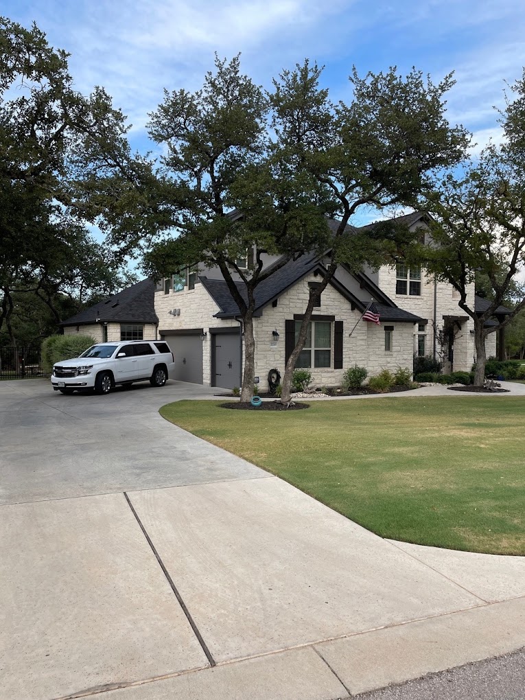 Two-storey brick house with a pointed roof. a garage is partially visible on the left, and a tree partly obscures the right side of the house. clear blue sky in the background.