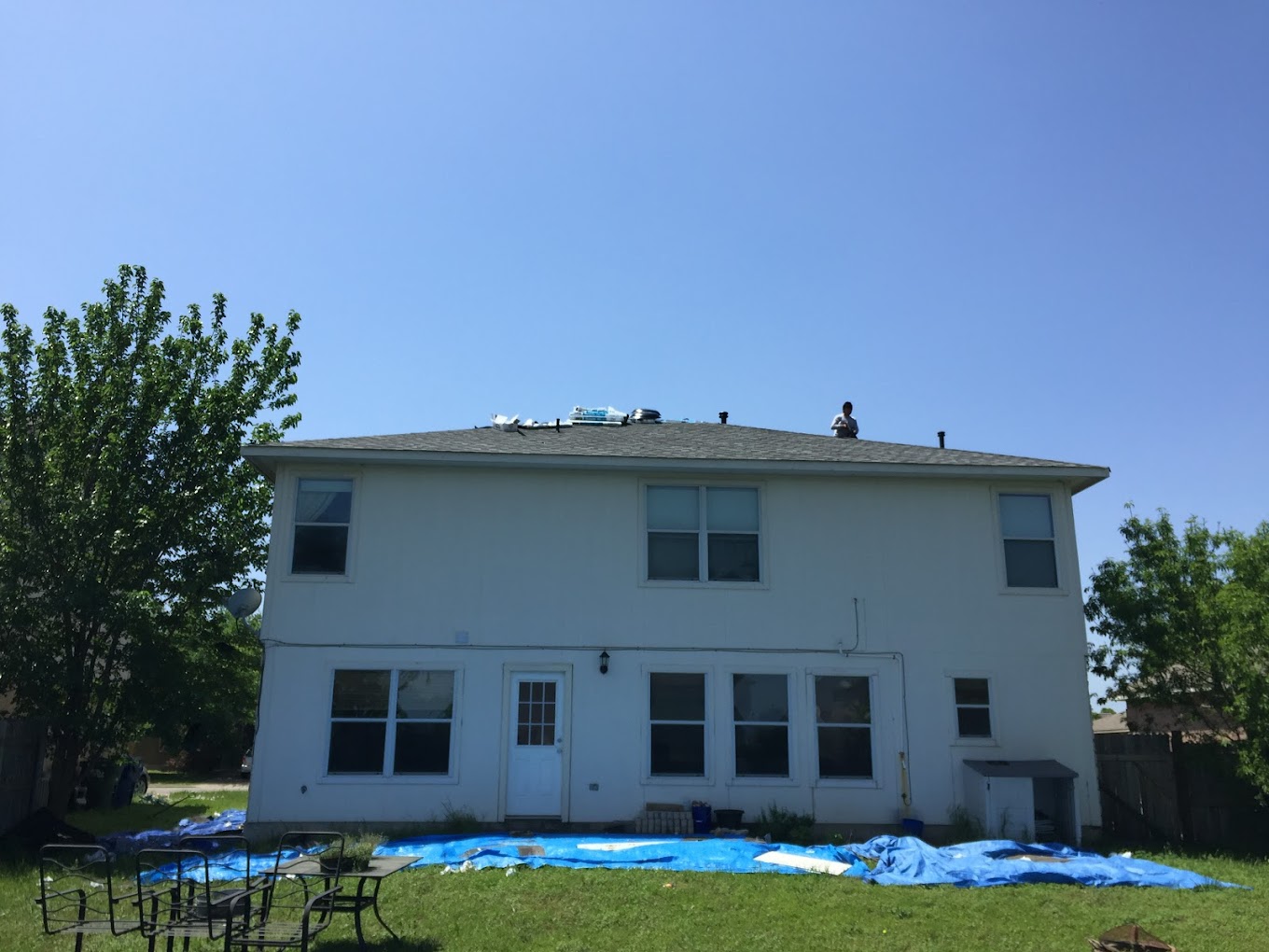 Two-storey brick house with a pointed roof. a garage is partially visible on the left, and a tree partly obscures the right side of the house. clear blue sky in the background.