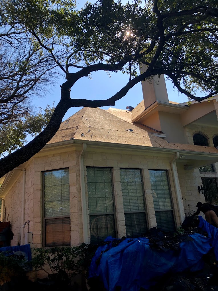 Two-storey brick house with a pointed roof. a garage is partially visible on the left, and a tree partly obscures the right side of the house. clear blue sky in the background.